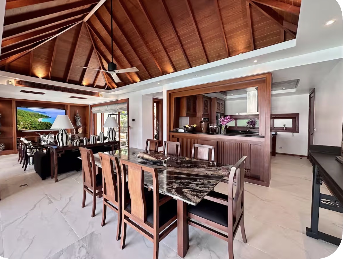 Open living and dining area with a vaulted teak ceiling and marble dining table